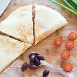 Greek Style Quesadilla Wedges On Cutting Board with Olives and Tomatoes