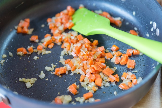 sauteed Carrots and Onion in Skillet with Green Spatula