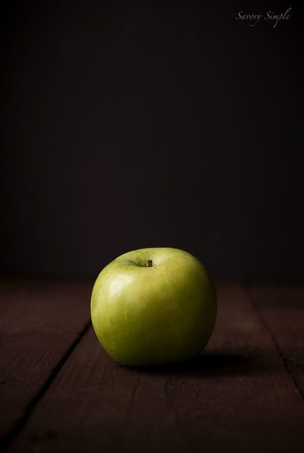 A green apple sitting in the dark