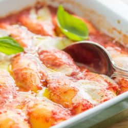 Stuffed Shells In Green Casserole Dish with Basil Leaves and Spoon