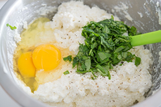 Ricotta Cheese, Eggs, and Chopped basil in Mixing Bowl