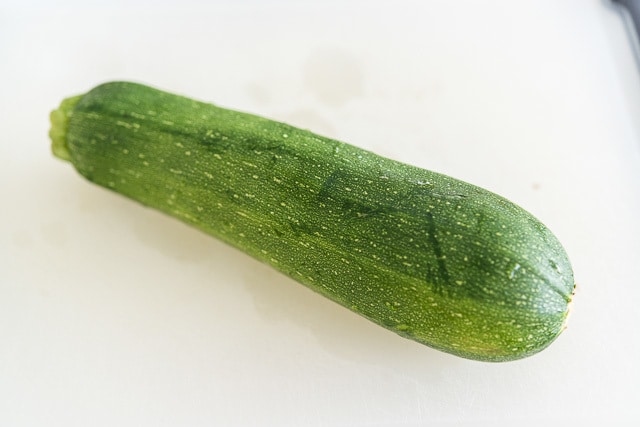 A close up of a zucchini on a board