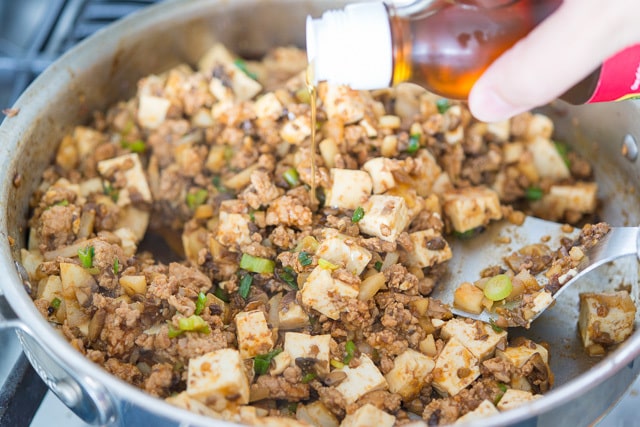 Drizzling Sesame Oil Over the Ground Turkey Lettuce Wraps Filling in the Skillet