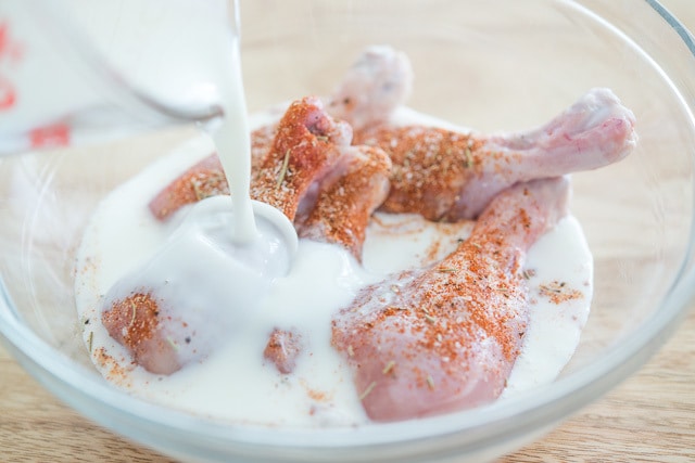 Pouring Buttermilk Over Seasoned Drumsticks