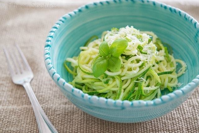 Zucchini Noodles in Blue Serving Bowl with Basil Garnish and Cheese On Top