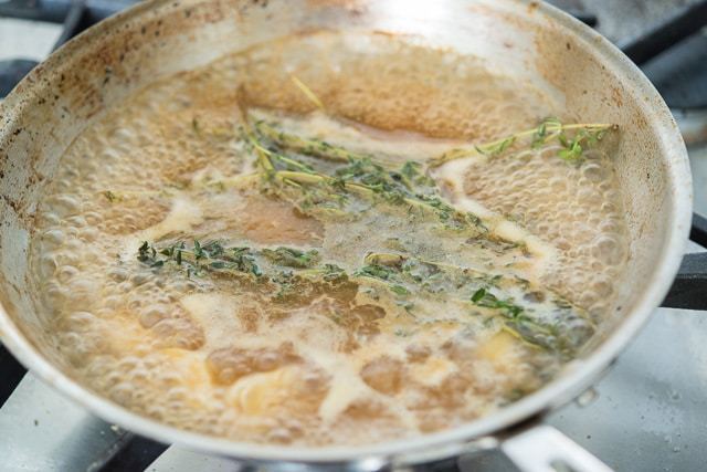 Boiling Gravy with Herbs in Stainless Skillet