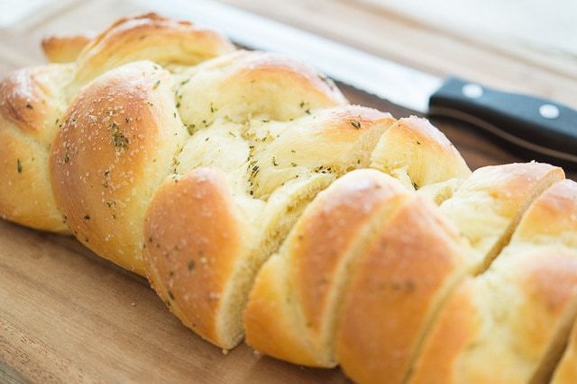 A close up of rosemary bread braid on cutting board