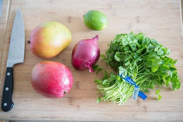 Cilantro Bunch, Mangoes, Red Onion, and Lime on Wooden Board