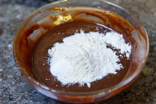Chocolate wet Ingredients in Glass Bowl with Flour and Leavener Added On Top