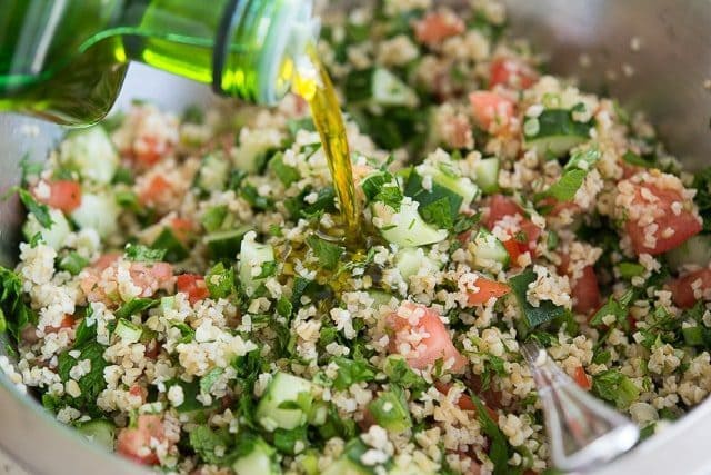 Adding Olive Oil to Tabbouleh Ingredients in Bowl