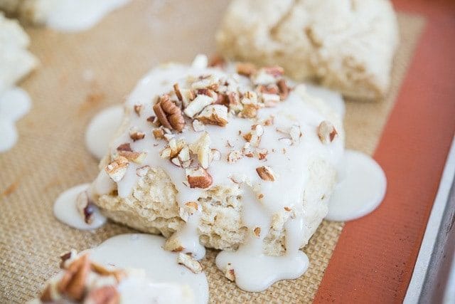 Maple Buttermilk Scones Recipe - Soft, fluffy scone with a sweet maple glaze and chopped pecans on top.