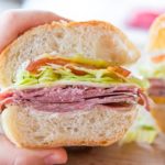 Italian Sandwich Held By Hand to Show Interior View with Meats and Filling