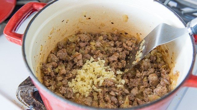Adding Minced Garlic to Browned Sausage in Pot