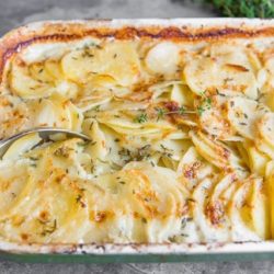 Potato Gratin In Casserole Dish with Spoon and Thyme