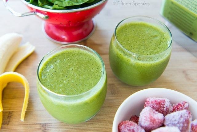 Morning Green Smoothie - In Two Glasses with Frozen Berries and Spinach in Colander