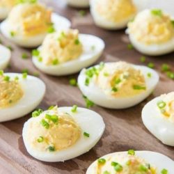 Rows of Deviled Eggs on a Cutting Board with Chives