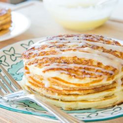 Cinnamon Roll Pancakes Stacked on a Plate with Cream Cheese Icing Drizzle