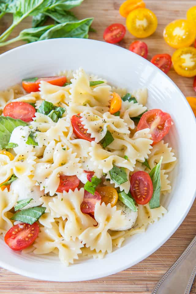 Caprese Pasta Salad - in White Bowl with Fresh Basil and Grape Tomatoes