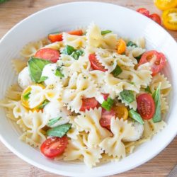 Caprese Pasta Salad in White Bowl with Fresh Basil and Grape Tomatoes
