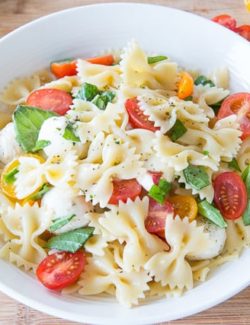 Caprese Pasta Salad in White Bowl with Fresh Basil and Grape Tomatoes