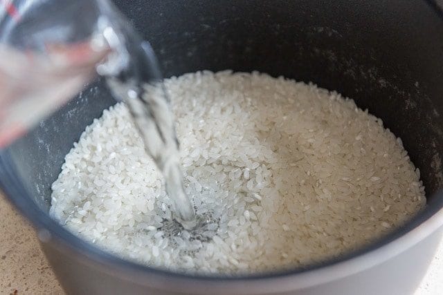 Pouring Water Into Rice Cooker Container with Rice