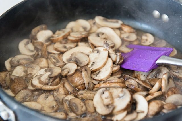Sliced Mushrooms in Skillet with Purple Spatula