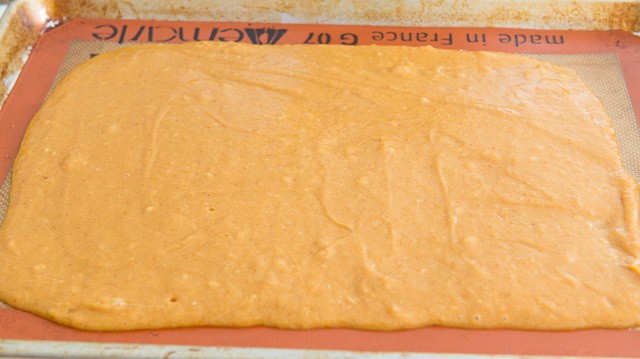 Pumpkin Roll Cake Batter Spread in a Rectangle on Silicone Mat Unbaked