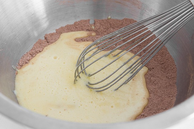 Cocoa Flour Mixture In Bowl with Egg Oil Mixture On Top with Whisk