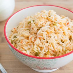 Mexican Rice In a Bowl with Spoon on Wooden Board