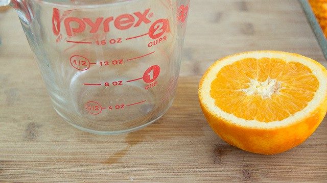Halved Orange and Measuring cup on Cutting Board