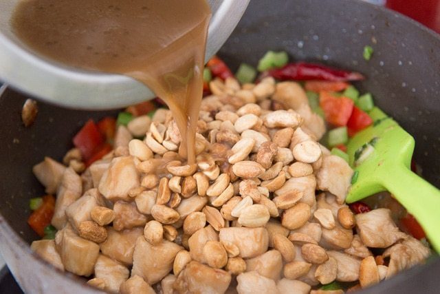 Pouring Kung Pao Sauce over Peanuts, Chicken, and Vegetables in Pan