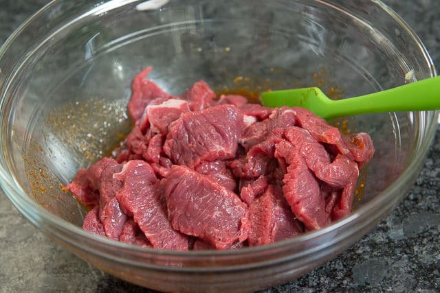 Sliced Raw Beef Added to Sauce in Glass Bowl