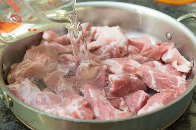 Pouring Water Over Pork Butter Chunks in Saucepan