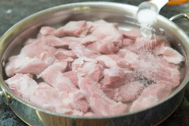 Adding Salt Over Pork Shoulder Chunks in Saucepan