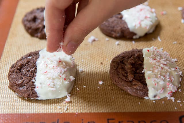 Sprinkling Crushed Candy Canes Onto White Chocolate Dipped Chocolate Cookies