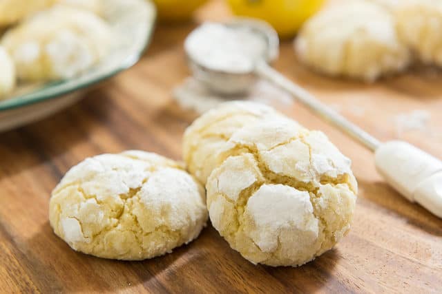 Lemon Crinkle Cookie Recipe - On A Wooden Board With Powdered Sugar Sprinkling Wand