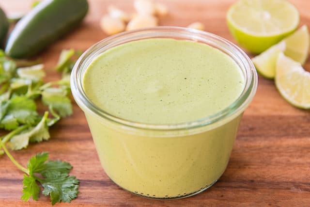 Cilantro Jalapeno Sauce - in Glass Jar with Garlic and Lime in Background
