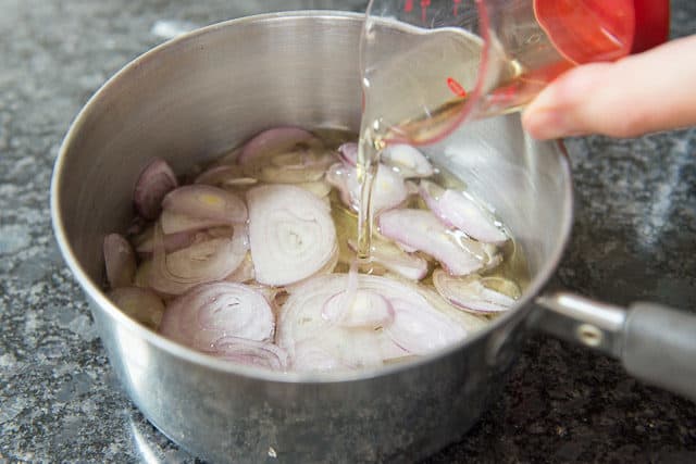Sliced Shallots In Small Stainless Steel Saucepan With Oil
