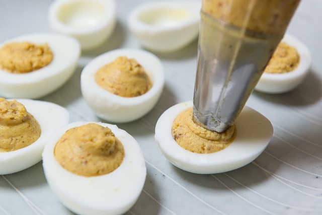 Piping Deviled Egg Mixture Into Hardboiled White Halves For Deviled Eggs