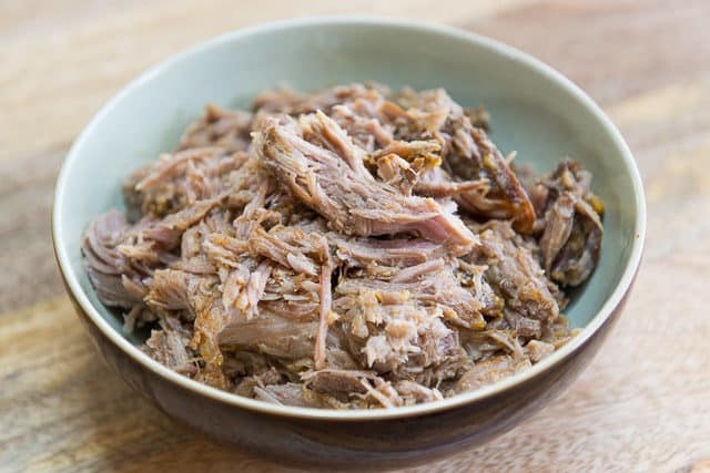 Pulled Pork Seasoned With Sazon Mix In Green And Brown Ceramic Bowl