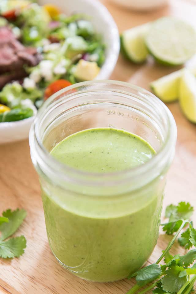 Cilantro Lime Dressing In Glass Jar with Salad in Background