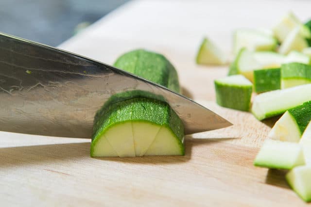 Knife Dicing Fresh Zucchini on Board
