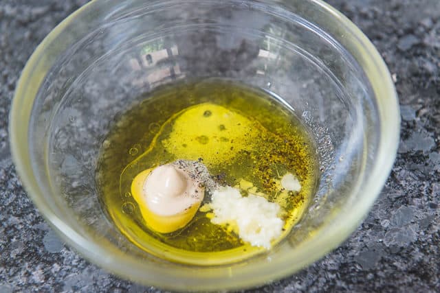 Olive oil, vinegar, garlic, Dijon in glass bowl