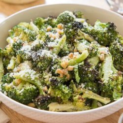 Charred Broccoli in White Bowl with Pine Nuts and Cheese On Top