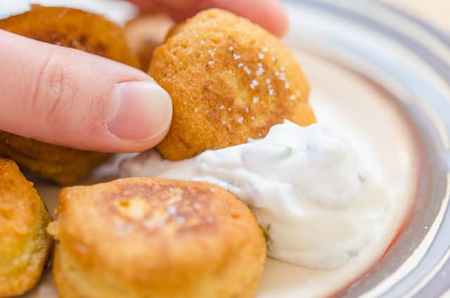 Dipping a Chickpea Fritter Into Yogurt Dip on a Plate
