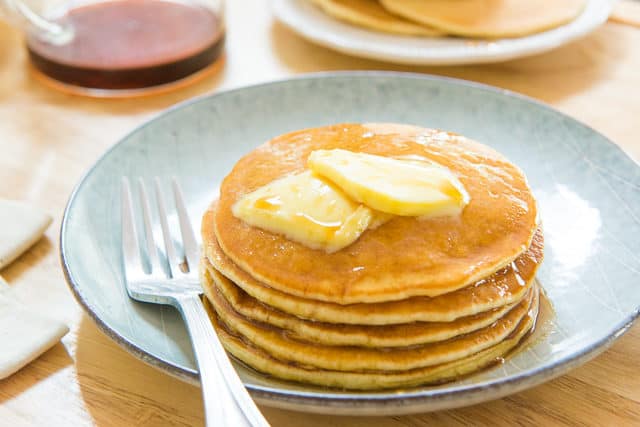 A Stack of Homemade Buttermilk Pancakes on a blue Plate with Butter and Syrup