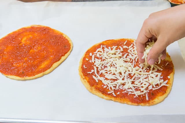 Sprinkling Cheese Over Tomato Sauce Spread On Crust