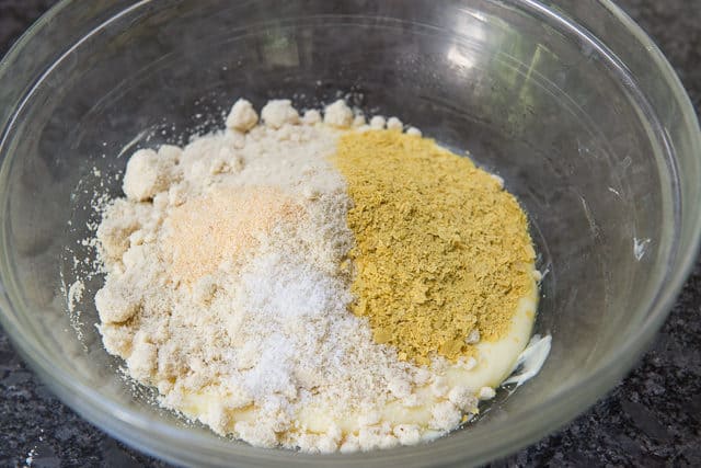 Nutritional Yeast, Almond Flour, Garlic, and Seasoning Added to Melted Cheese in Glass Bowl