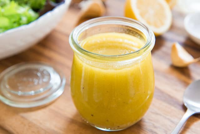 Lemon Vinaigrette Recipe - Stored in Small Glass Jar with Salad Greens In Background