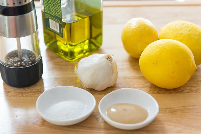 Lemon Vinaigrette Ingredients - On a Wood Board with Lemons, Garlic, Olive Oil, Pepper, Mustard, and Salt